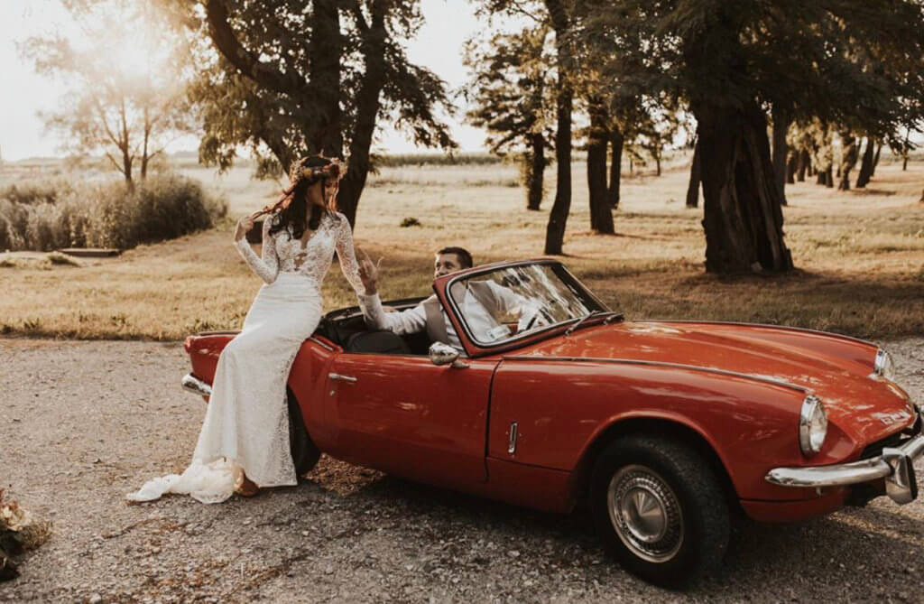 couple with a classic red wedding car