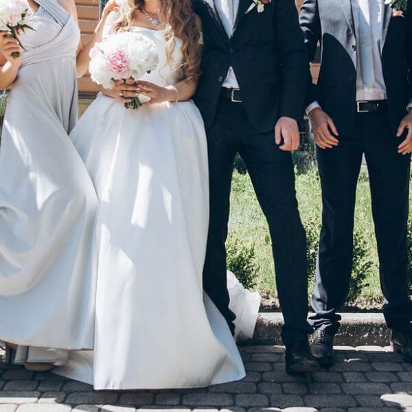 bride, groom, bridesmaids and groomsmen standing on a sunny wedding day