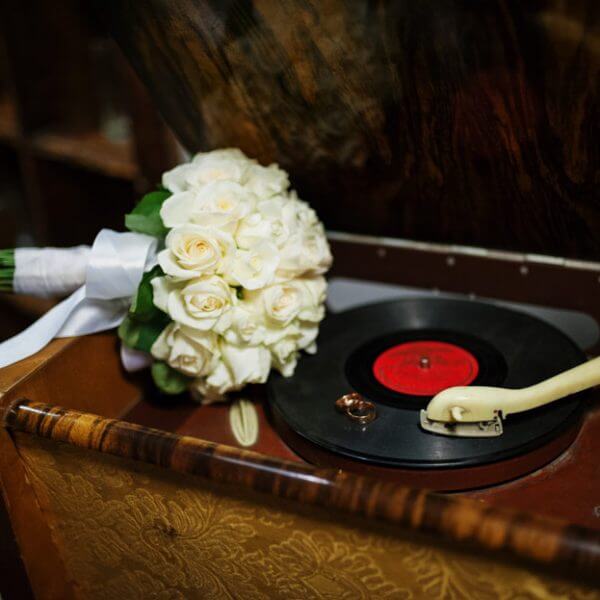flower bouquet and wedding rings on a vintage gramaphone